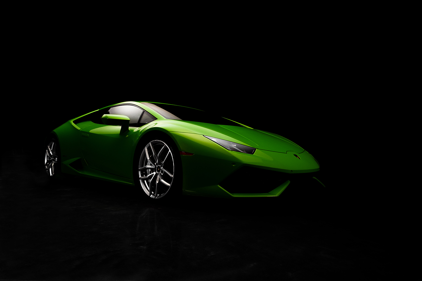 A three-quarter view of the front of a lime green Lamborghini Huracan in dramatic lighting
