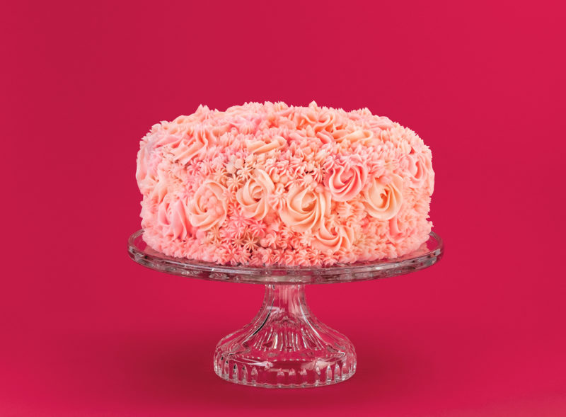 A photograph of a pink cake on a stand